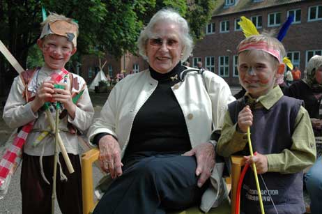 Umzingelt von den Indianern Bennet (links) und Leon (rechts): Stiftungs-Gründerin Anna-Maria Wendelborn. Die Steenkamp-Grundschüler feierten heute auch den Abschluss ihrer Projektwoche. Dabei wurden zum Beispiel am Haus der Jugend Indianerzelte bemalt. Foto: HELGE NORMANN 