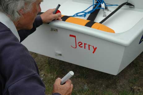Der 1. Vorsitzende des Clubs Uwe Ortgies beschriftete die neuen Boote: Die Optis heißen jetzt »Tom« und »Jerry«, der 420er »Kumulus« (nach der Wolkenart). Foto: HELGE NORMANN 