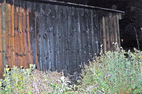Der Brand des Containers zog auch die Holzwand eines Schuppens in Mitleidenschaft.