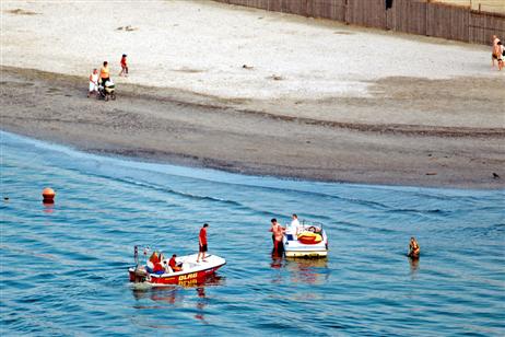 Sicherheit auf den Wasser. Das Rettungsboot läuft ein am Strand aufsitzendes Motorboot an und vergewissert sich, ob Hilfe notwendig ist. 