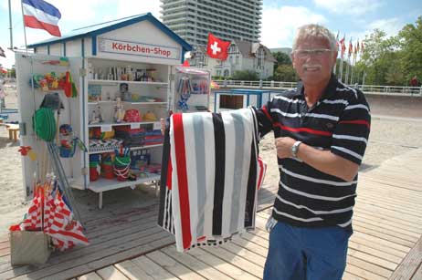 Strandkorbvermieter Jochum Aichholzer zeigt die gemusterten Handtücher, die aus dem Körbchen-Shop (hinten) entwendet wurden. Foto: TA