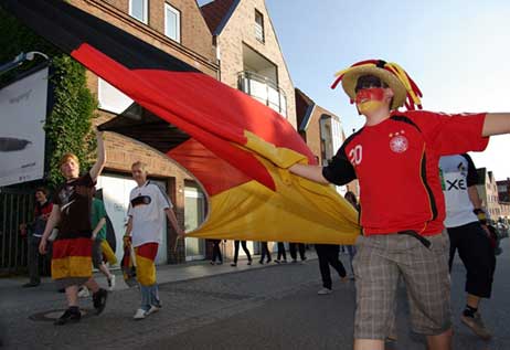 Buntes Bild: Die Fans ziehen durch die Kurgartenstraße, in den Hauseingängen stehen die Anwohner und gucken zu. Foto: CARMEN FRISCH