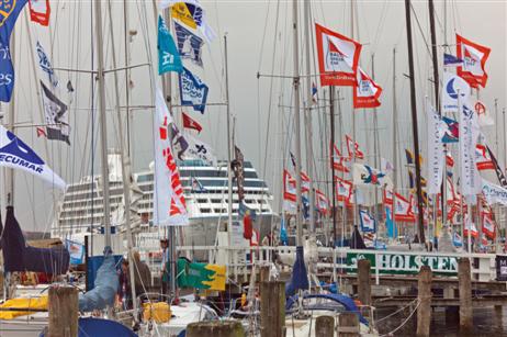 Fahnen- und Flaggengeschmücktes Ambiente an der Travepromenade. Im Hintergrund das Kreuzfahrtschiff AZAMARA.