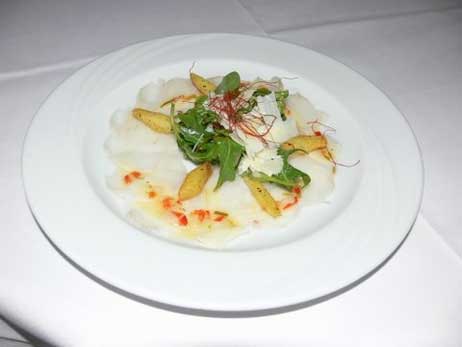 Die Vorspeise präsentierte sich als kleines Kunstwerk auf dem Teller: roh marinierte Seeteufelbäckchen in Limonen-Chili-Marinade mit Ruccolasalat, Parmesan und gerösteten Kartoffelrauten. Foto: CLAUDIA SCHMÄING 