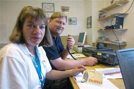 Claudia Schmäing (l) hält eine so genannte »QSL-Karte« in der Hand. Sie trägt in großen Buchstaben das Internationale Rufzeichen der Amateurfunkstation in Travemünde, DL0TO. Mit QSL-Karten bestätigen die Funkamateure eine Funkverbindung, ergänzt um viele technische Details, die für die Gegenstation sehr wichtig sind.