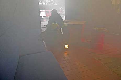 Die Feuerwehr ist alarmiert und bewegt sich auf dem Fußboden kriechend am Brandort.