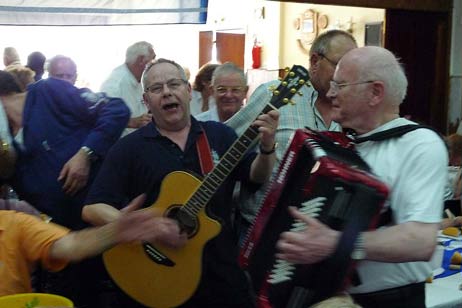 Die Stimmung brachten die beiden Musiker der Combo des Passat Chores noch einmal auf den Höhepunkt. Spontan machten sich auf den Weg durch den Saal. Krystian Hollenstein mit der Gitarre und Siegfried Wiebus, Akkordeon. Foto: KARL ERHARD VÖGELE 