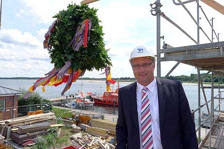 WSA Amtsleiter Henning Dierken neben dem Richtkranz auf dem Neubau WSA Verkehrszentrale. 